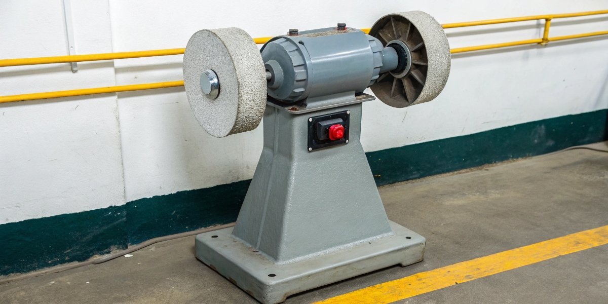 A standard pedestal grinder with clear warning labels indicating "No Aluminum" and "No Magnesium."