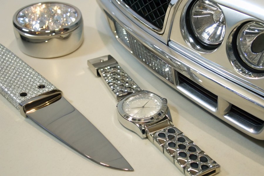A shot of a variety of brilliantly shiny products: a chrome car bumper, a silver watch, and a polished knife blade