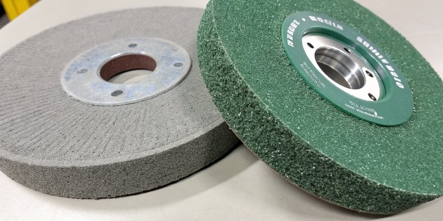 A close-up shot comparing a gray aluminum oxide wheel and a green silicon carbide wheel side-by-side