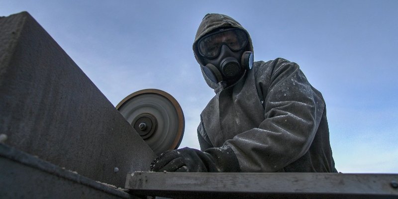An operator wearing full PPE including a respirator and safety glasses next to a [grinding machine](https://www.science.org/content/blog-post/machines-rise-bit-more)[^2]