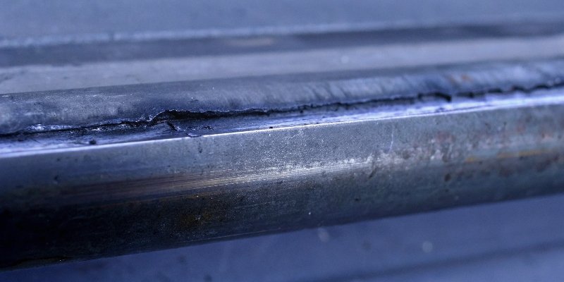 A very wide, burn-marked cut in a metal bar caused by using a grinding wheel for cutting