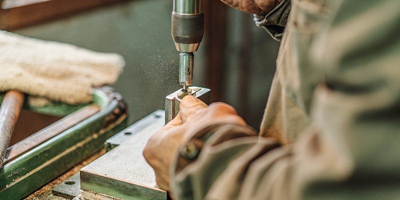 An operator using a small mounted point on a die grinder to deburr the inside of a metal part