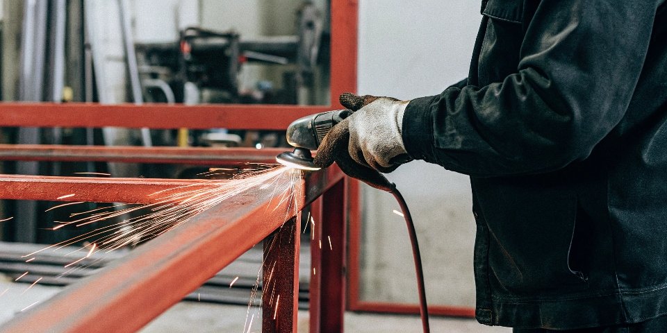 A worker using a corded angle grinder with sparks flying