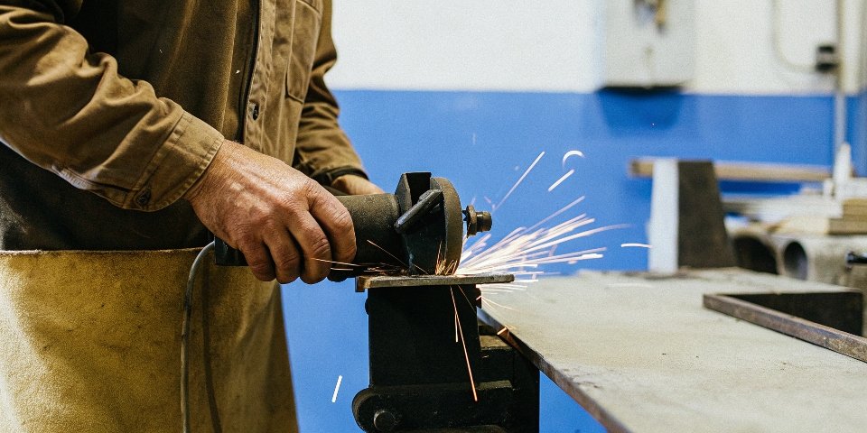 a person shaping a piece of metal on a bench grinder