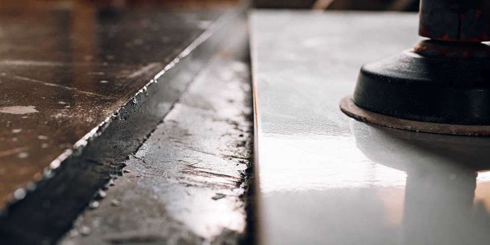 A close-up split-screen image showing a rough metal surface versus a mirror-like finish-ground surface.