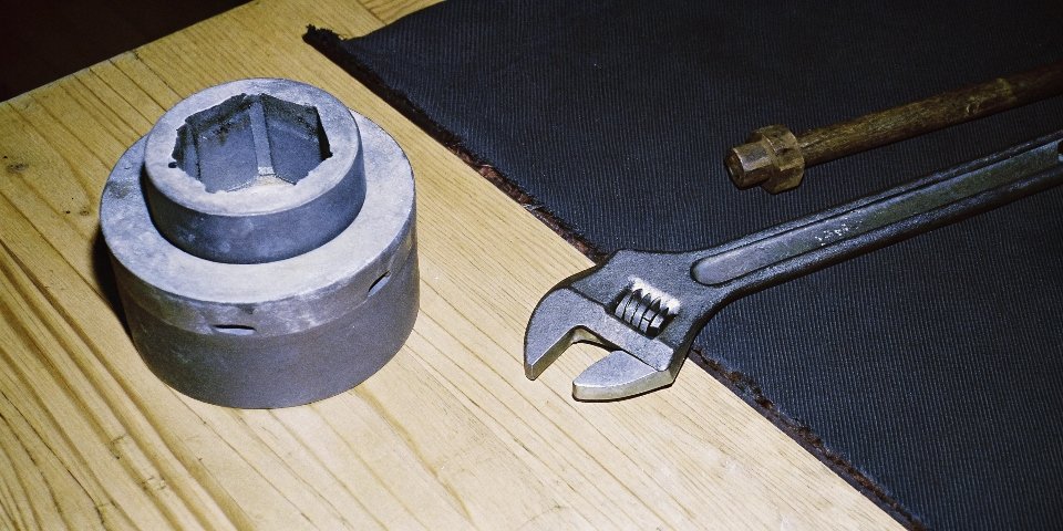 A picture of a rounded and damaged grinder nut next to a proper wrench.