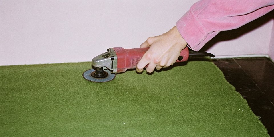 A hand holding an angle grinder spanner wrench, showing a counter-clockwise motion to loosen.
