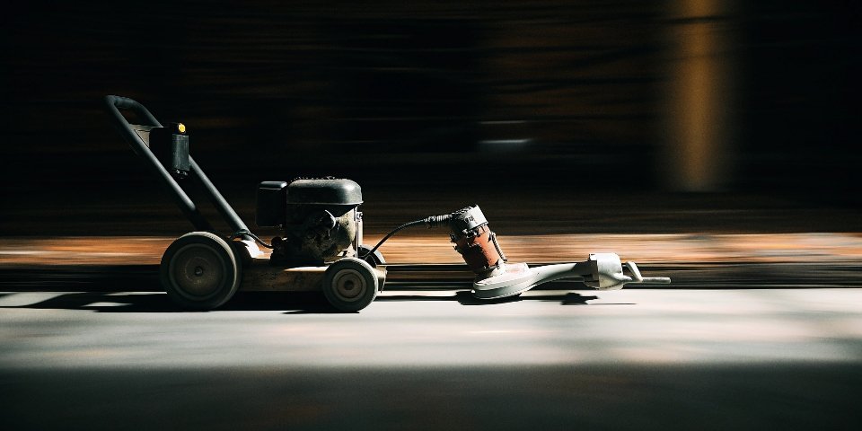 A large walk-behind concrete grinder next to a small handheld angle grinder, showing the size difference.