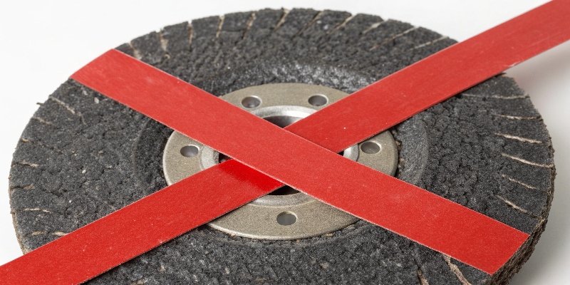 A cracked grinding wheel with a red X over it to show danger.