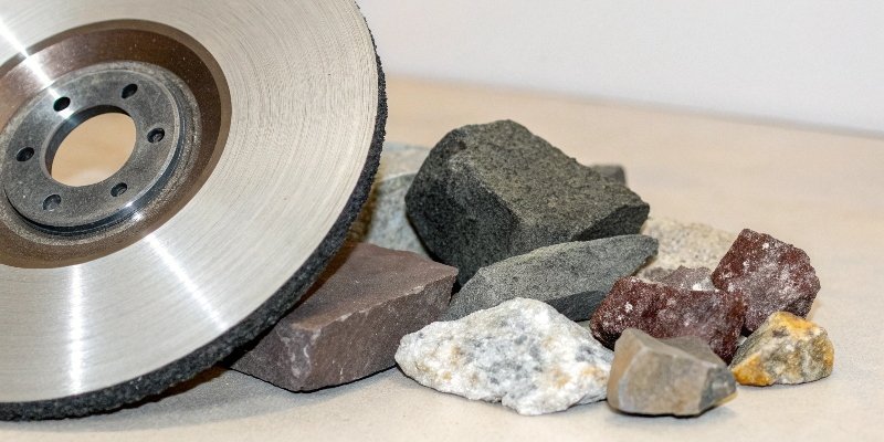 A collection of raw abrasive minerals and a finished grinding wheel