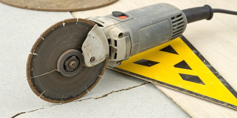 An angle grinder with a cracked disc and a danger symbol over it.